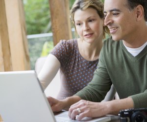 Couple uploading photos to laptop computer