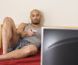 African man watching television in bed