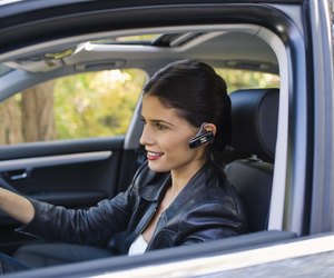 Woman in car with cell phone earphone