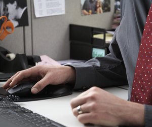 Office worker using computer at desk, mid section, close-up