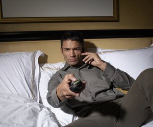 Man lying on bed, watching television
