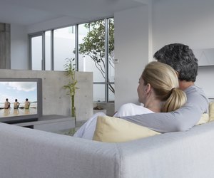 Couple relaxing on sofa watching television, rear view