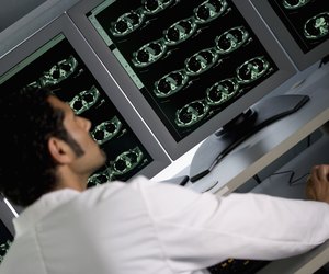 Rear view of doctor in front of MRI monitor screens