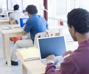 People in office working on computers, rear view