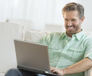 Happy Man Using Laptop On Sofa