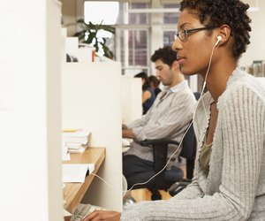 Female office worker at desk, wearing earphones