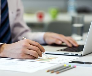 Business Person reading Data on paper Charts and Computer