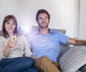 Couple watching a movie with a video projector on sofa
