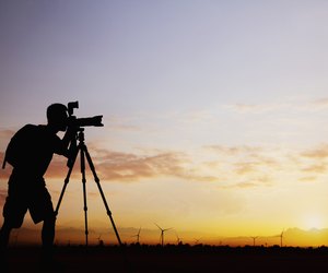 Silhouette of man taking photos with his camera at sunset with a dramatic sky