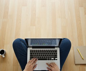 girl sitting on wooden floor laptop coffee cup and notebook