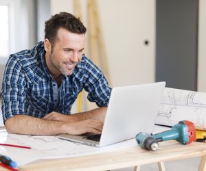 Smiling construction worker working with laptop