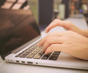 Female hands typing on keyboard of laptop