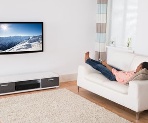 African Woman Lying On Sofa Watching Television