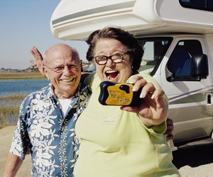 Senior couple taking photo of themselves by camper van