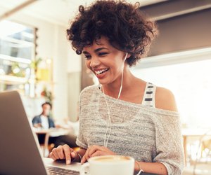 Happy woman at cafe using laptop