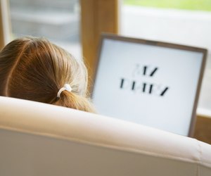Girl (5-7) sitting on sofa with laptop, rear view