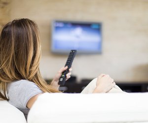 Young woman on couch watching a flatscreen tv