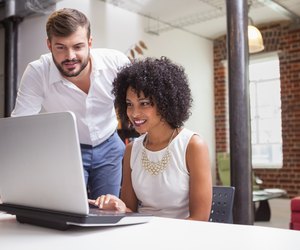 Casual business team looking at laptop together