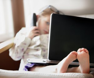 Child working on phone and computer