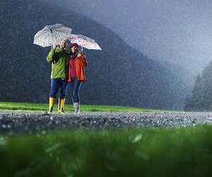 Man and woman with umbrellas playing in the rain.