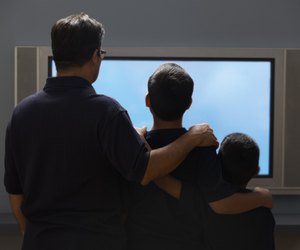 Father and sons watching a widescreen television