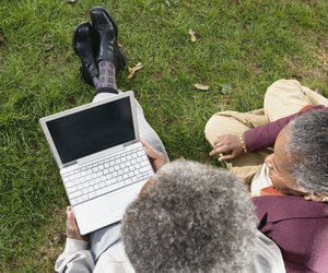 Senior African couple using laptop on grass outdoors