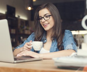 Beautiful hipster woman using laptop at cafe