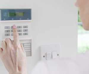 Woman Setting Control Panel On Home Security System