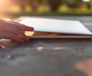 Man opening his laptop on a wooden table