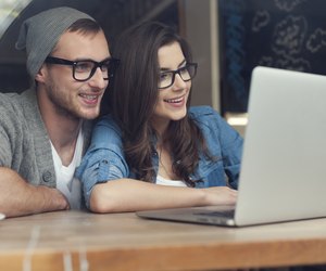 Stylish couple with contemporary laptop in cafe