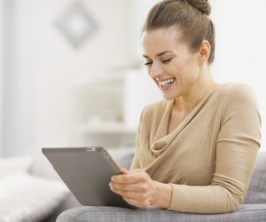 Smiling young woman sitting working on tablet pc