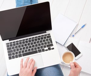 woman working at home at laptop with cup of coffee
