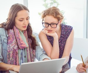 Two women well versed in fashion staring at laptop screen
