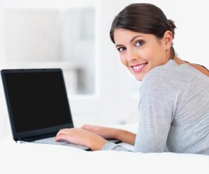 Young woman smiling in bed with a laptop