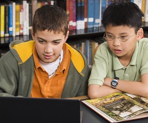 Boys using laptop in library