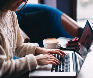 Smiling hipster girl using laptop
