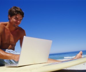 Low angle view of a young man using a laptop on a surfboard