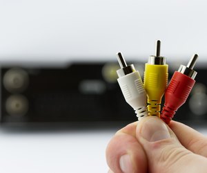 AV cable connectors in hand with AV receiver on background