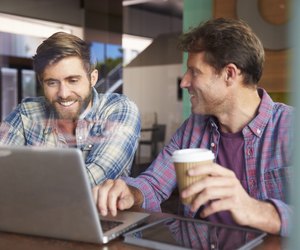 Two Businessmen Working On Laptop In Coffee Shop