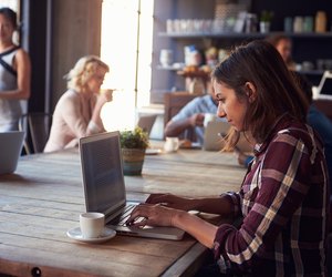 Interior Of Coffee Shop With Customers Using Digital Devices