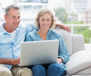 Cheerful couple relaxing on their couch using the laptop