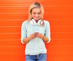 Fashion, technology and people concept - pretty smiling girl usi