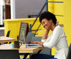 Happy woman using laptop at cafe