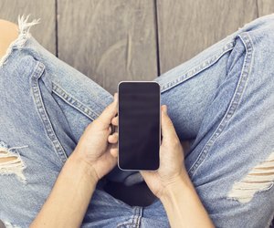 Girl in jeans with smartphone on the wooden floor