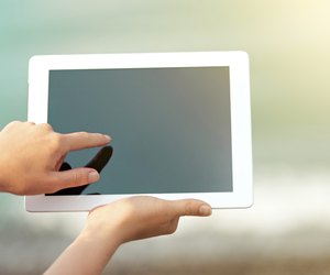 white tablet with a blank screen in the hands