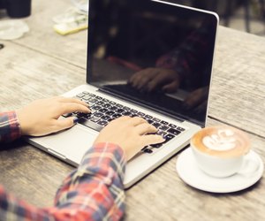 woman typing on a laptop with cup of coffee