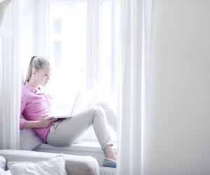 Teenage girl suing laptop in window