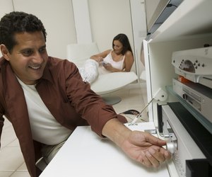 Man Adjusting Dial on Stereo