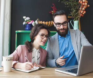 Modern team working in cafe with laptop, smartphone with coffee