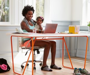 Woman holding child using computer at home after exercising